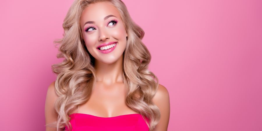Smiling woman in a pink dress with matching pink eyeshadow and lipstick, showing how matching your makeup to your outfit creates a cohesive look.