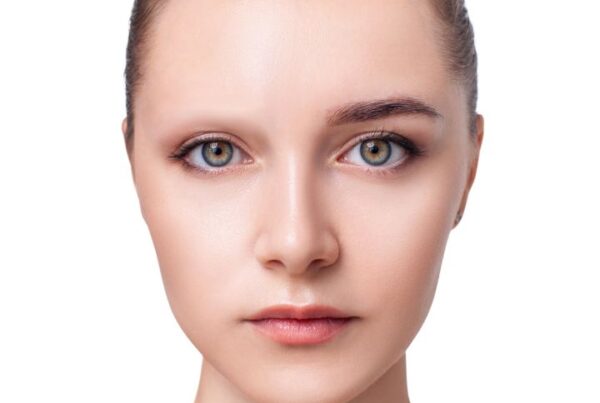 Model with one eyebrow covered and one natural, showing how to cover eyebrows for special FX makeup.