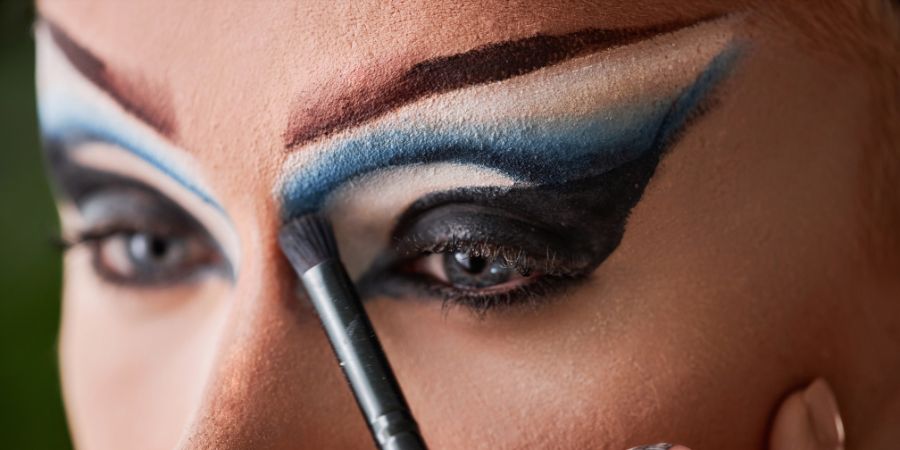 Close-up of drag makeup application with bold brows and eyeshadow, showing how to cover eyebrows for creative makeup looks.