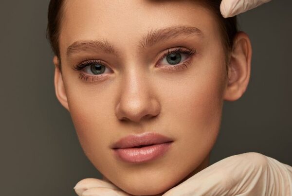 Close-up of a woman with flawless skin being examined by gloved hands, representing professional skincare services and guidance on how to become a skincare consultant.