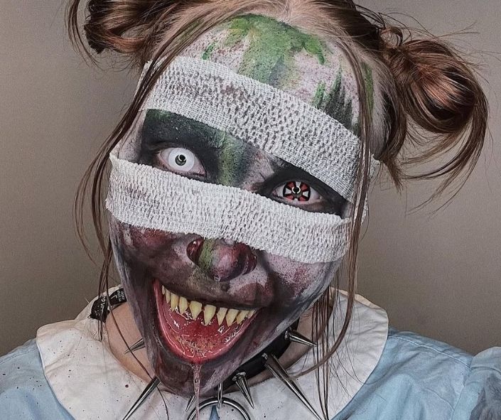 Terrifying scary Halloween makeup featuring bloody bandages, sharp fake teeth, creepy contact lenses, and smudged face paint for a nightmare-inducing look.