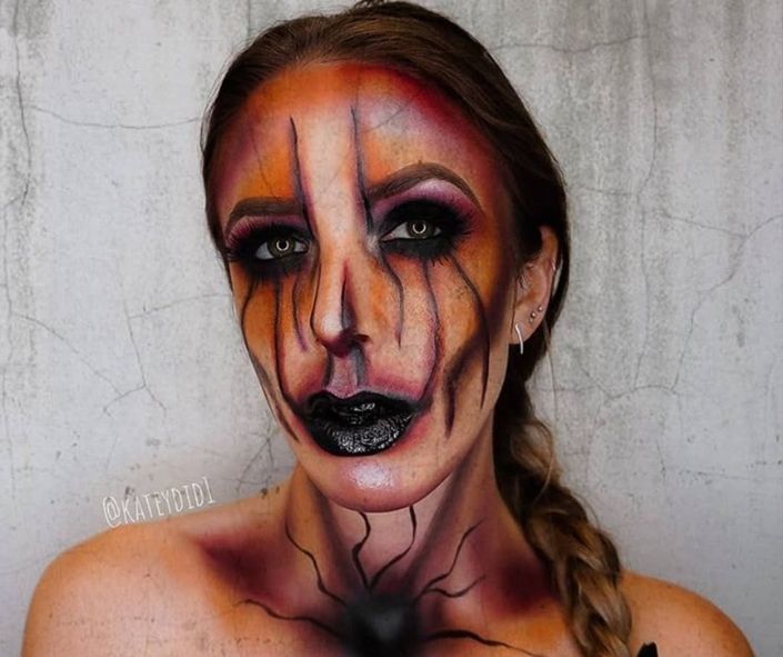 Creepy Halloween makeup idea inspired by Pennywise, featuring orange and black face paint, dark eye makeup, and cracked line effects for a scary clown look.