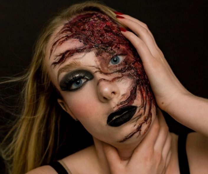 Scary Halloween makeup featuring a gory burned face effect with realistic special effects, black lipstick, and dramatic smoky eye makeup for a chilling look.