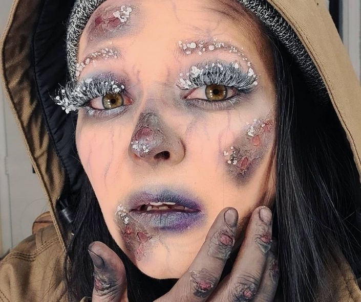 Scary Halloween makeup featuring a frozen zombie look with frosted lashes, pale cracked skin, and icy wound effects for a chilling undead style.