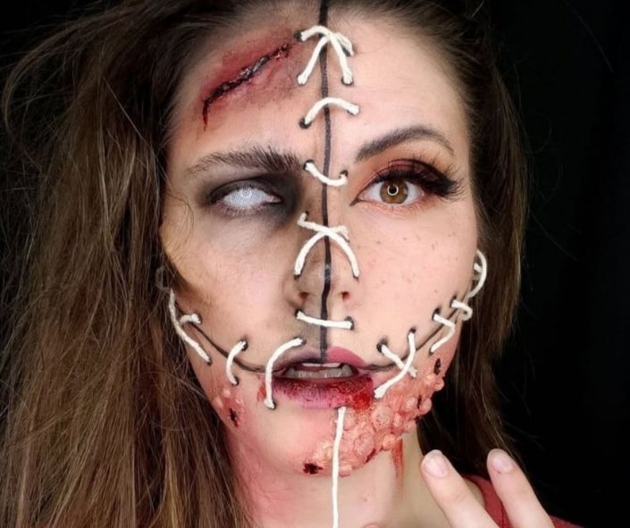 Scary Halloween makeup featuring a stitched-face effect with bloody wounds, exposed flesh, and dramatic contact lenses for a gruesome special effects look.
