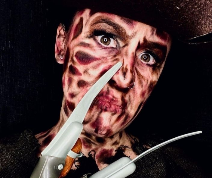 Scary Halloween makeup inspired by Freddy Krueger, featuring realistic burned skin effects, intense eye makeup, and razor claw props for a terrifying horror look.
