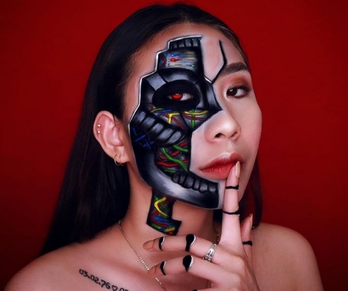 Scary Halloween makeup featuring a half-cyborg design with robotic face paint, colorful wiring details, and bold shading for a futuristic special effects look.