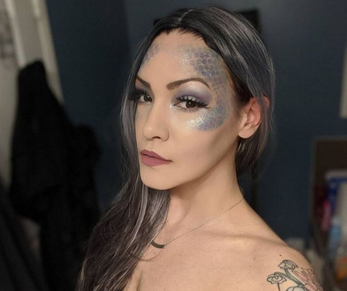Creative Halloween makeup idea featuring a shimmering mermaid-inspired look with silver scales, glitter accents, and soft purple eye makeup for a mystical effect.