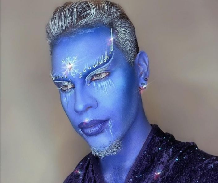 Creative Halloween makeup idea featuring an icy blue fantasy look with shimmering snowflake designs, jeweled accents, and frosty white details for a mystical effect.
