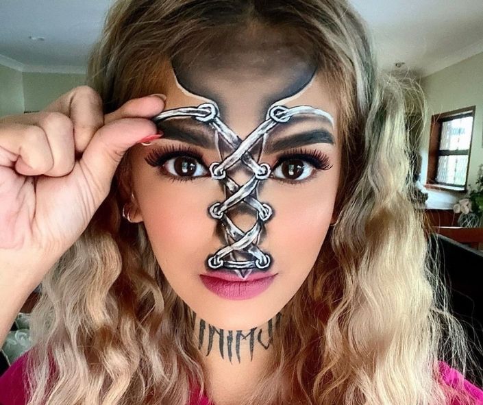 Creative Halloween makeup idea featuring a lace-up face illusion design with bold eye makeup, long lashes, and detailed special effects for a striking look.