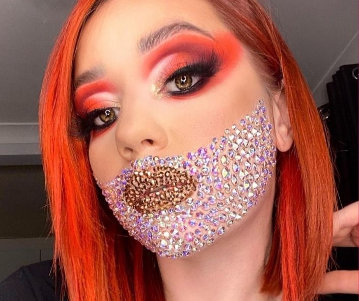 Creative Halloween makeup idea featuring bold red and black eye makeup paired with sparkling rhinestone face art and metallic lips for a glamorous costume look.