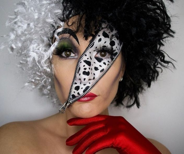Creative Halloween makeup idea inspired by Cruella de Vil, featuring a zipper face illusion with Dalmatian spots, dramatic green eye makeup, and bold red lips.