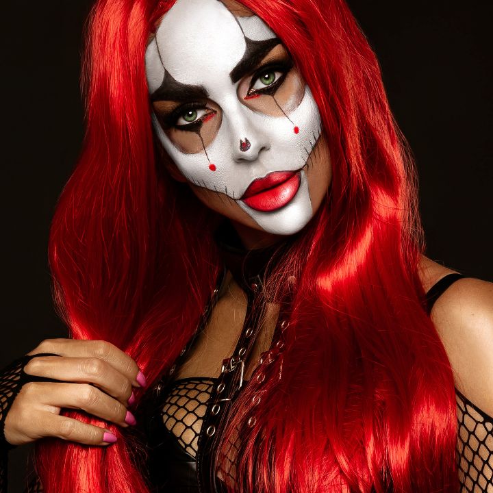 Halloween makeup look featuring a scary clown design with bold eye makeup, red wig, and stitched face details – perfect for spooky Halloween makeup ideas.