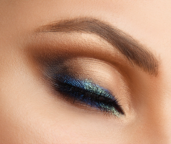 Close-up of shimmering blue and gold eyeshadow with defined eyeliner, creating a captivating glitter bridal makeup look for modern brides.