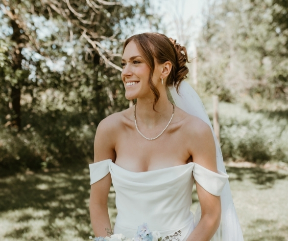 Radiant bride with natural glow and soft glam look, showcasing a timeless bold bridal makeup style paired with an off-the-shoulder wedding gown.