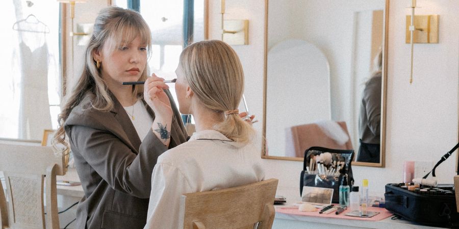 Makeup artist, Elena Franklin, applying foundation to a bride in a studio, showcasing professional techniques and elegant bride makeup ideas for wedding day looks.