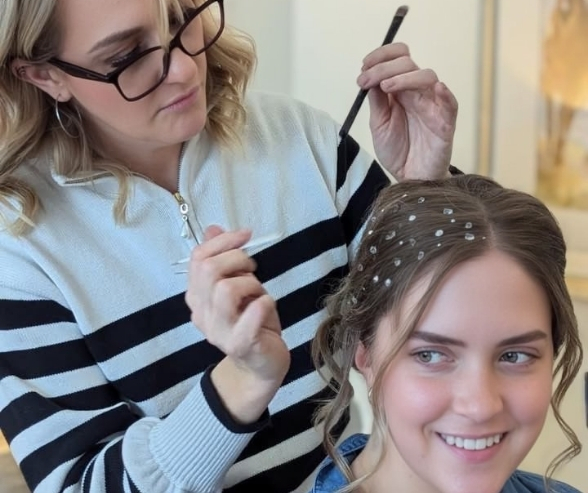 Makeup artist Kate Loveland styling a client’s hair with pearl accents, capturing behind-the-scenes makeup inspiration and professional artistry in action.