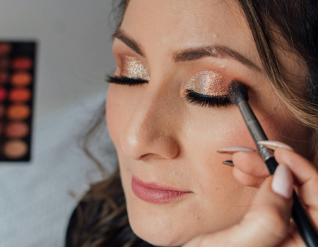 Professional eyeshadow application featuring gold shimmer on the eyelids