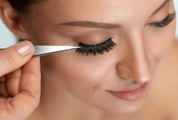 applying false eyelashes to female model's eye