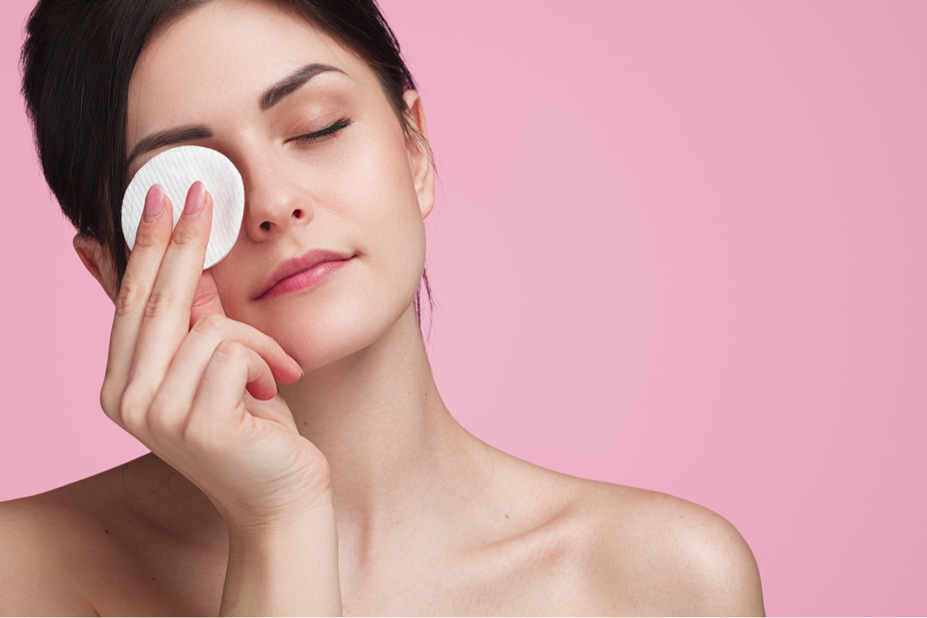 makeup hygiene - girl removing eye makeup with cotton pad
