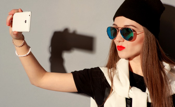 Girl with sunglasses taking a picture of herself with her phone
