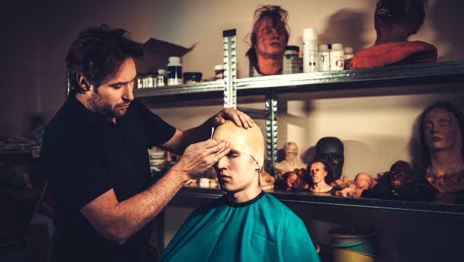 Makeup artist applying an actor's prosthetics