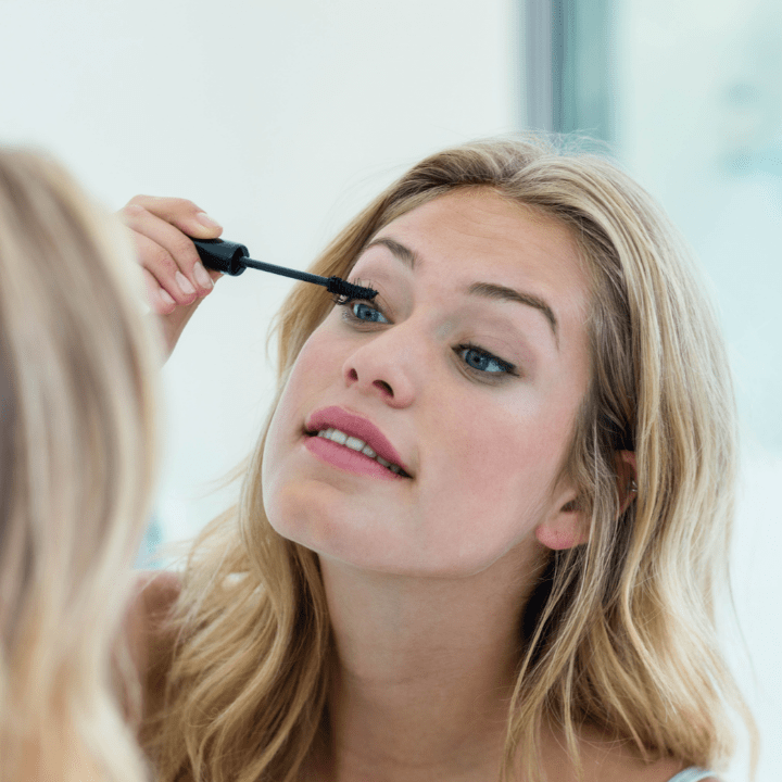 girl applying mascara on herself before attending makeup school