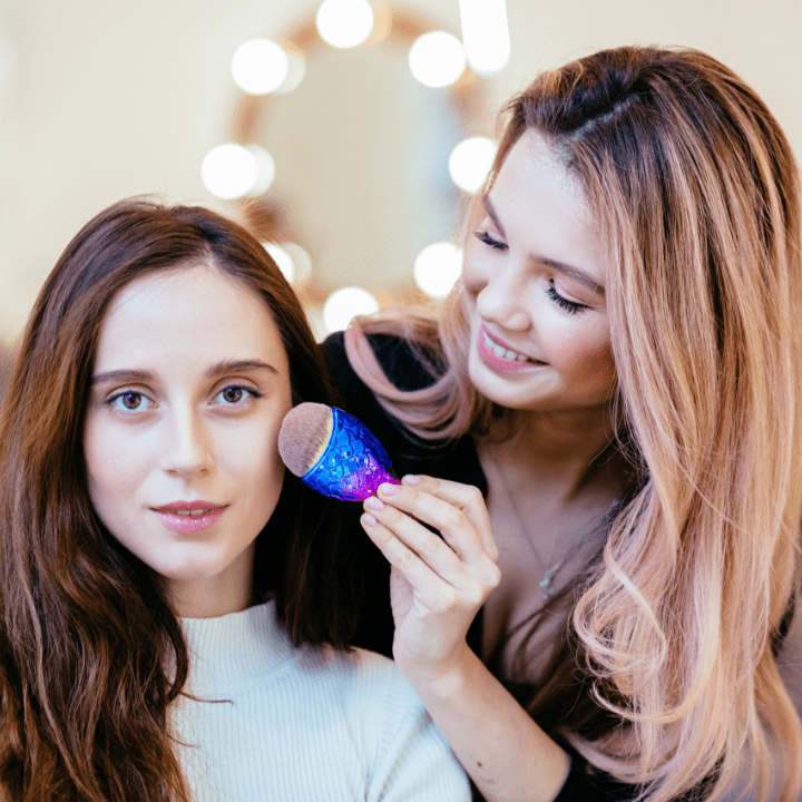 female mua doing makeup on client's cheek