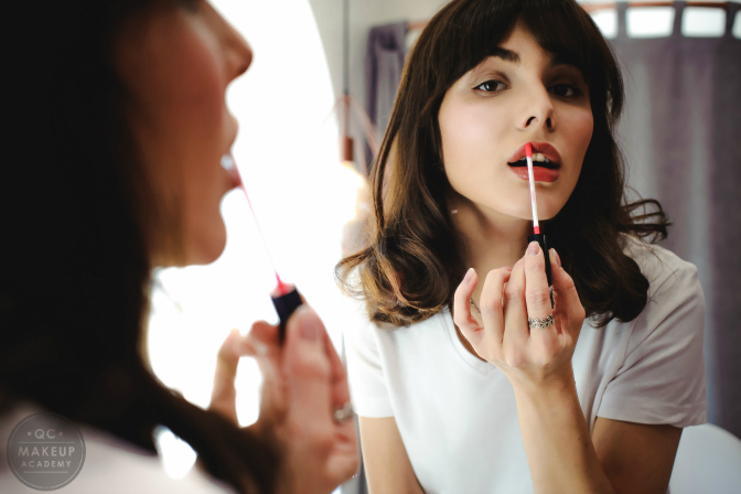 woman applying lipstick in mirror