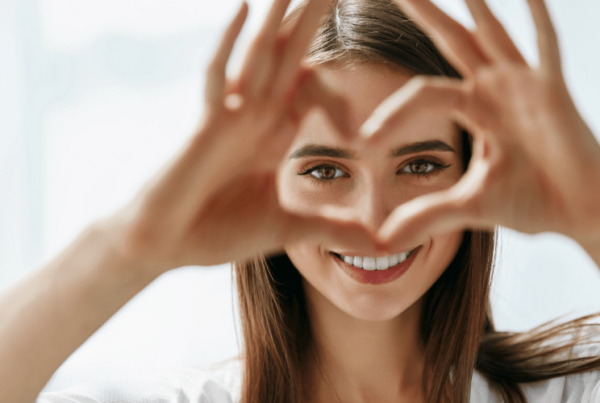 smiling woman making heart symbol with fingers