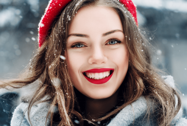 model outside in the snow, with beautiful brows, lashes, and red lip makeup