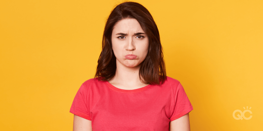 young woman pouting, standing in front of yellow background