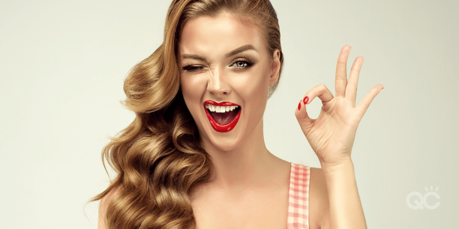 Pin-up retro girl with curly hair winking, smiling and showing OK sign . Presenting your product. Expressive facial expressions