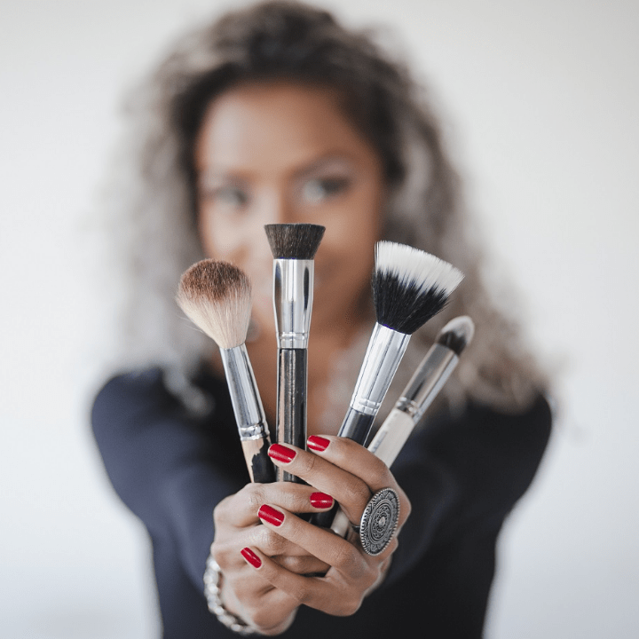 makeup artist holding up makeup brushes