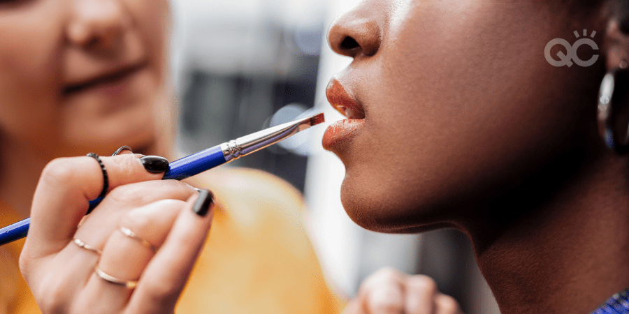 makeup artist applying lip product to dark skin model's lips
