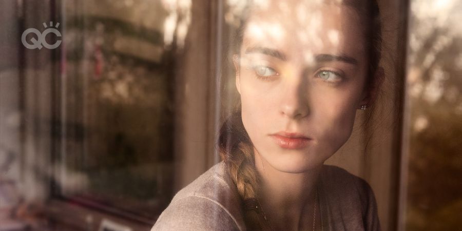 Sad young woman looking out window