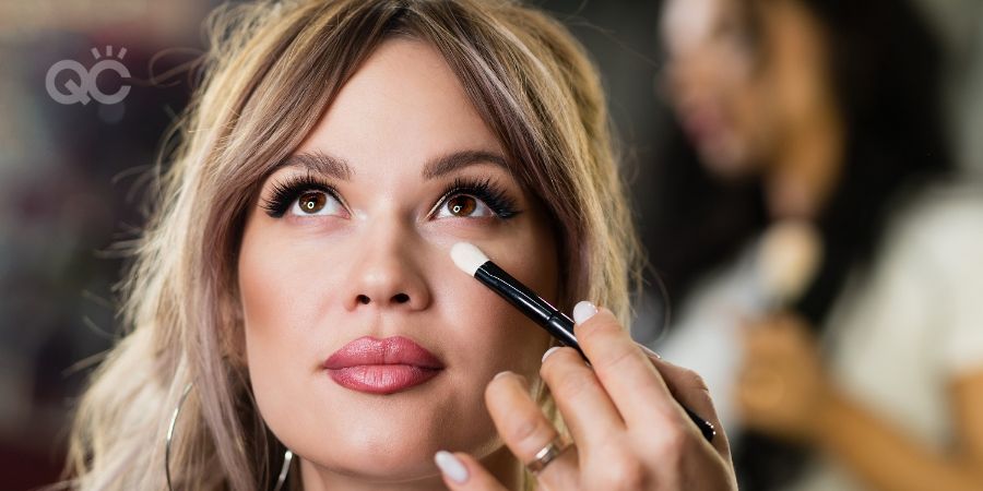 Makeup Artist Applying Corrector On Flawless Fresh Skin Doing Make Up. Female Eye with Long False Eyelashes. Cosmetics, Beauty. Close up. Real People. Perfect Glamorous Evening Makeup