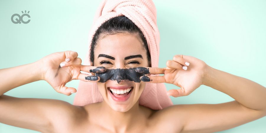 Happy smiling girl applying facial charcoal mask portrait - Young woman having skin care cleanser spa day - Healthy beauty clean treatment and cosmetology products concept