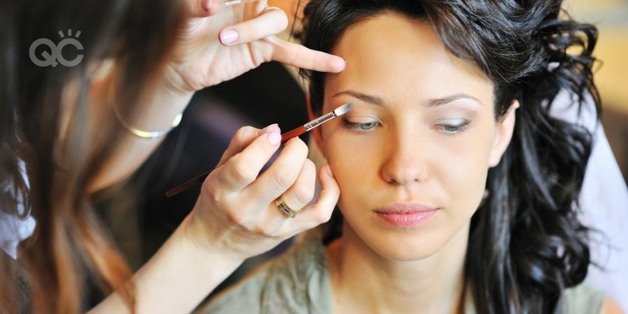 Young beautiful bride applying wedding makeup by makeup artist