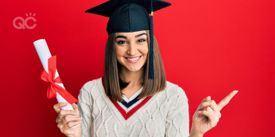Young brunette girl holding graduate degree diploma smiling happy pointing with hand and finger to the side