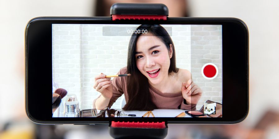 Young beautiful Asian woman professional beauty vlogger or blogger recording make up tutorial video by smartphone to share on social media. Makeup business.