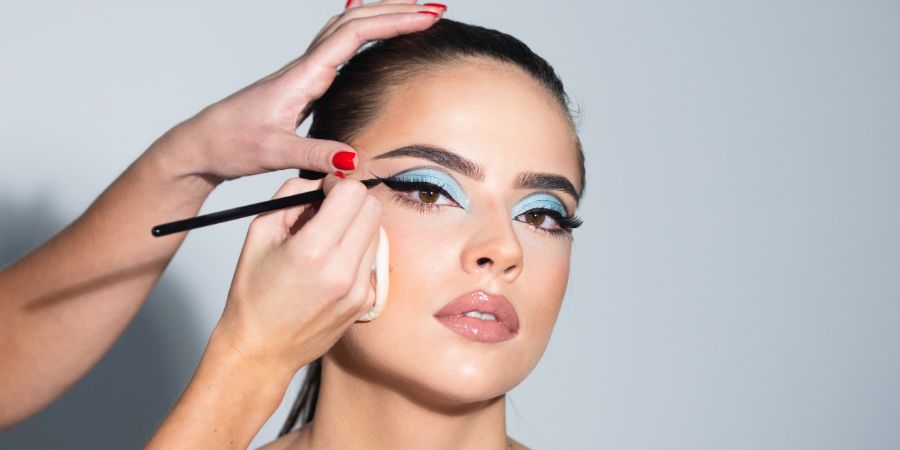 Beautiful woman face with perfect makeup. Makeup artist applies eye shadow. Hand of visagiste, painting cosmetics of young beauty model girl. Beauty girl with perfect skin. Market makeup business article.