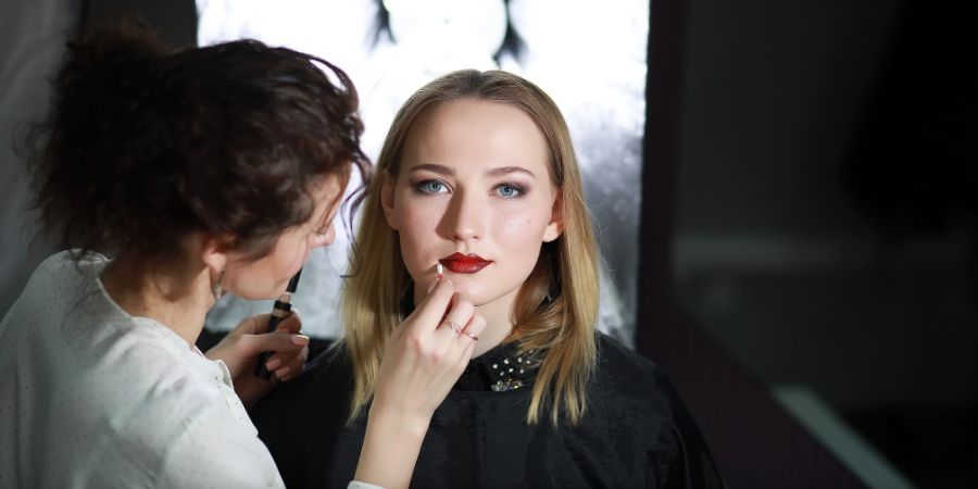 Young girl with a make-up artist in the studio in front of a mirror. Makeup article.