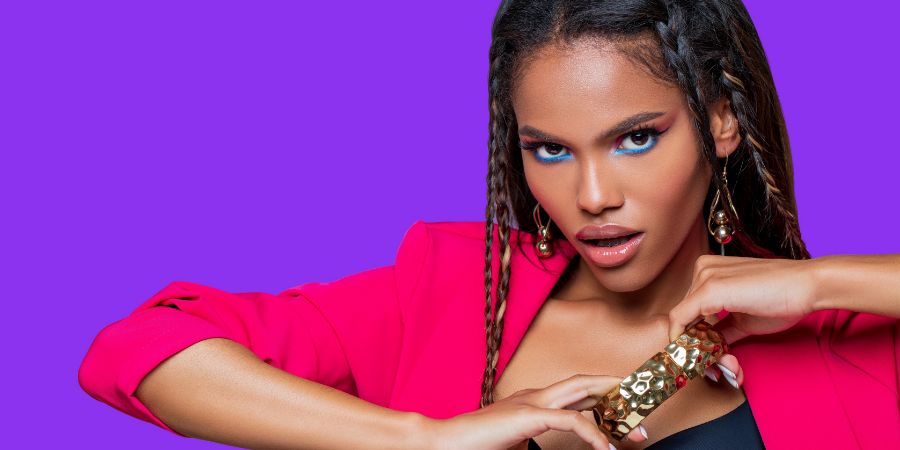 Fashion African American model in gold jewelry, with perfect bright makeup and pigtails. Beautiful stylish African model on colored background. Makeup photoshoot article.